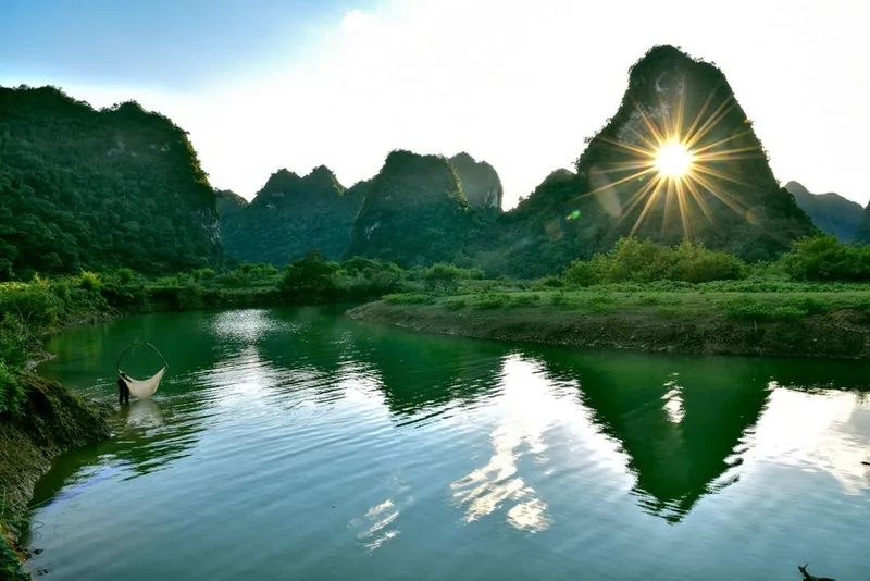 Hoàng hôn sau những ngọn núi đá vôi phản chiếu trên dòng sông xanh yên bình ở Cao Bằng.
